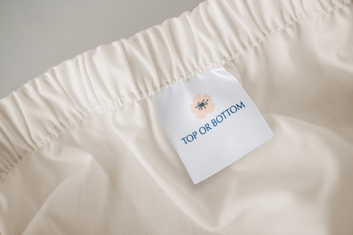 Fitted organic cotton natural sheet showing american blossom linens tag.