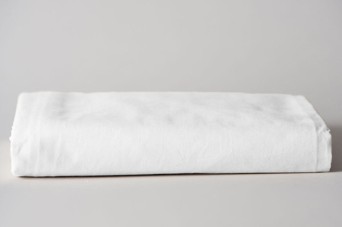 Crib sheet organic in white folded.