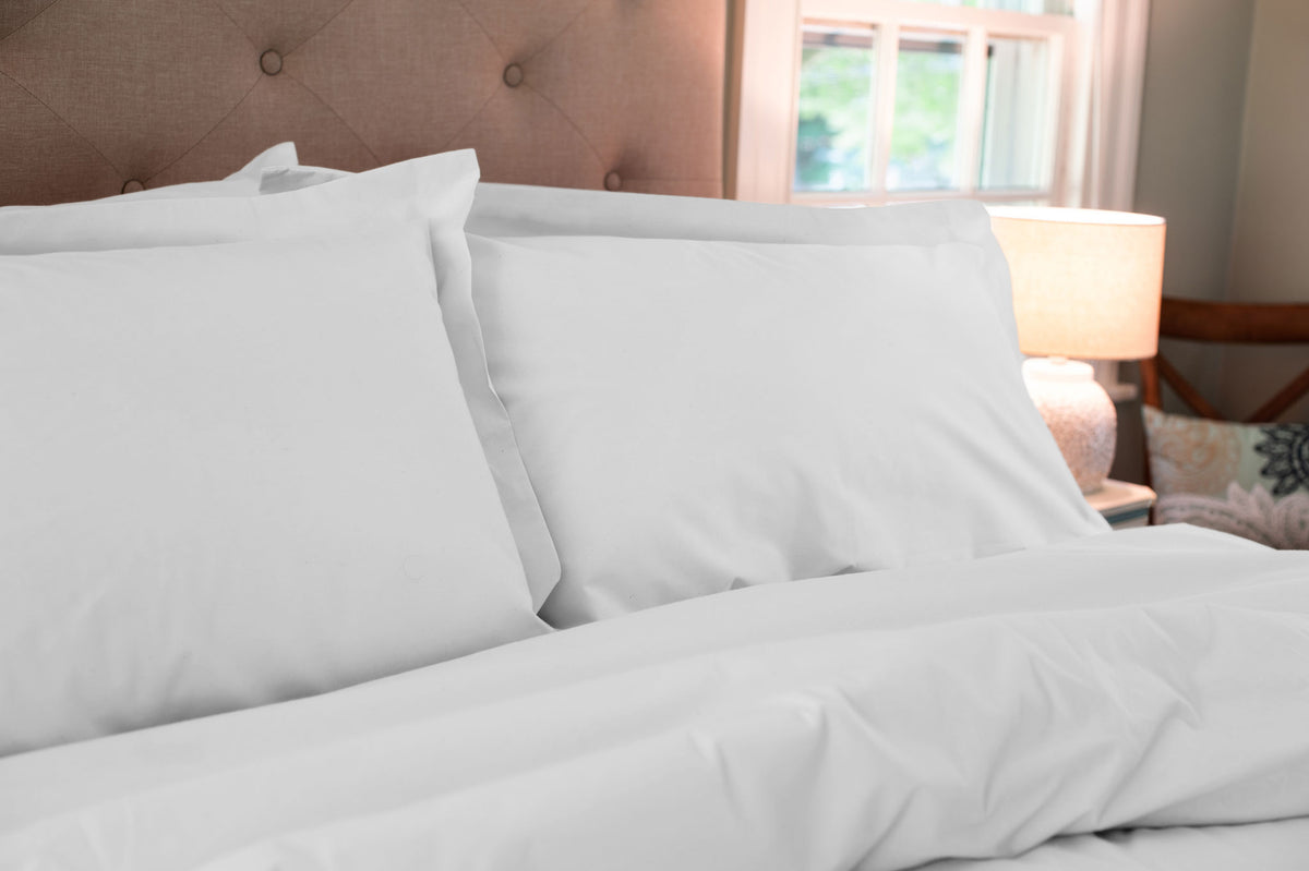 White organic cotton pillow shams with pillows on a made bed.