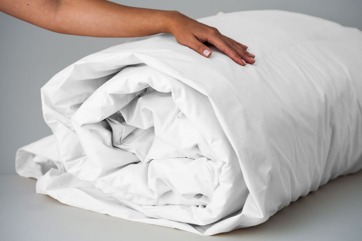 White organic cotton duvet cover rolled up with insert.