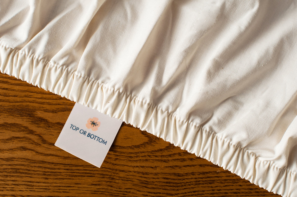 Organic cotton fitted sheet in natural color showing american blossom linens tag.