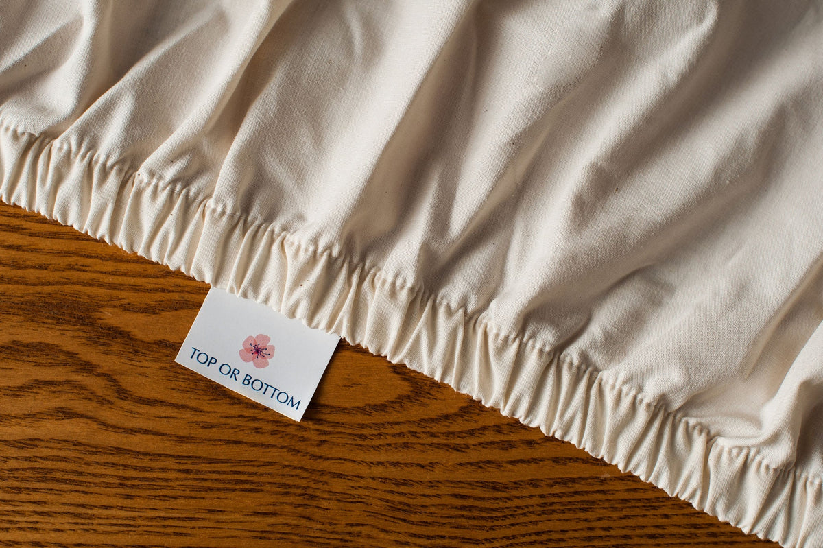 Organic cotton fitted sheet in natural color showing american blossom linens tag.
