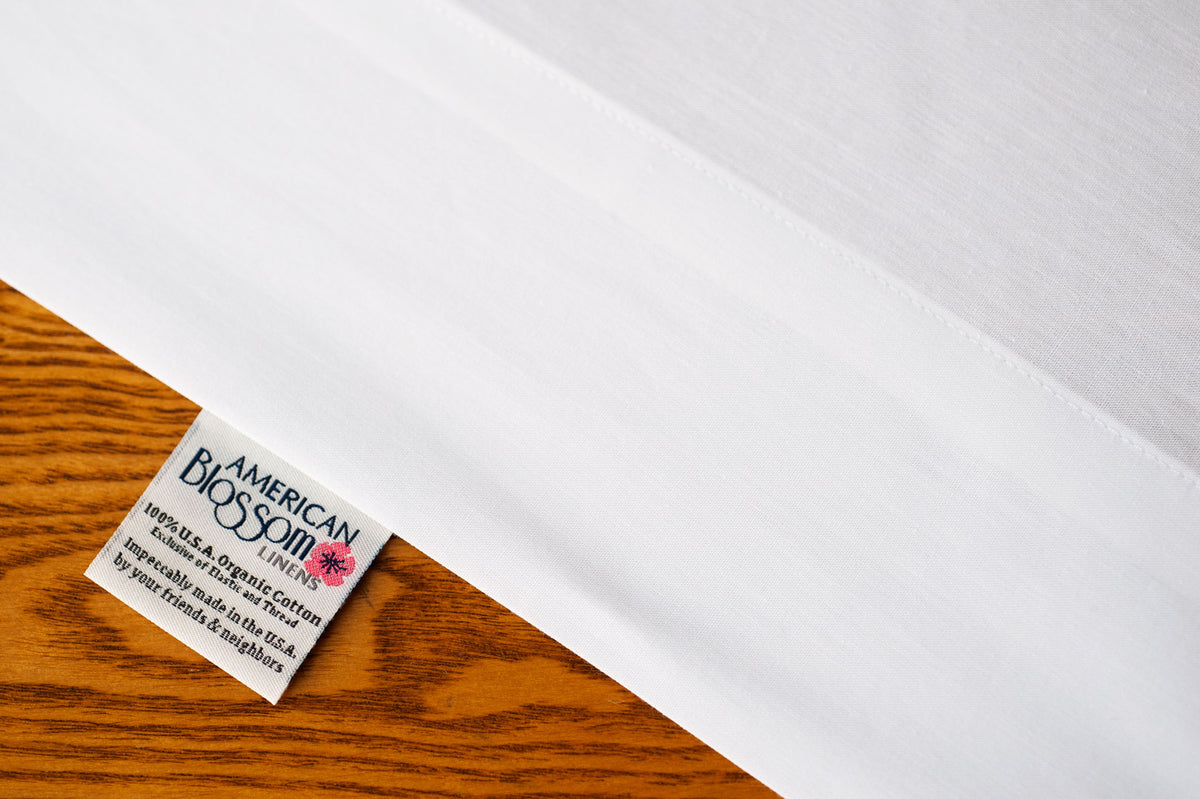 Flat organic cotton sheet showing american blossom linens tag.
